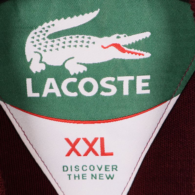 Närbild av Lacoste-logotyp och storleksmärkning XXL i nacken