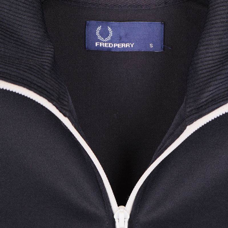 Närbild på Fred Perry-logotyp och storleksetikett i kragen