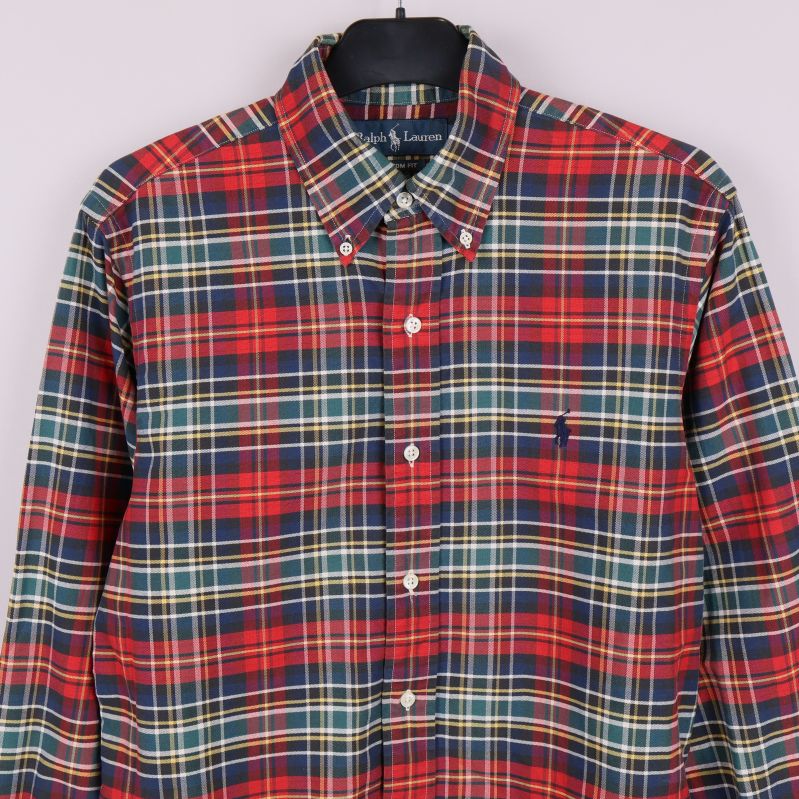 Framdel av rutig skjorta med synliga knappar och bröstlogga