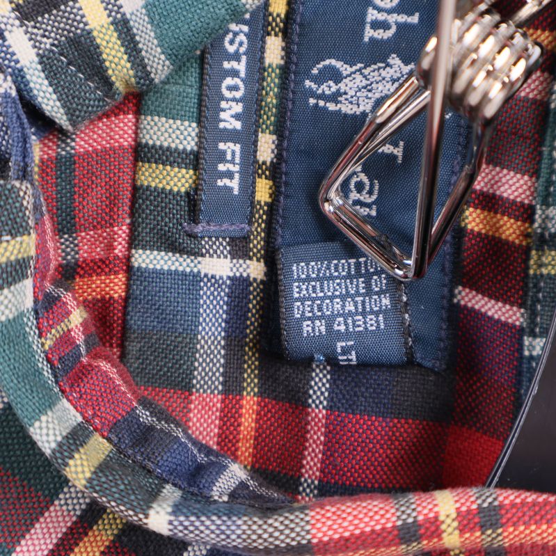 Materialetikett som visar 100% bomull i skjortan