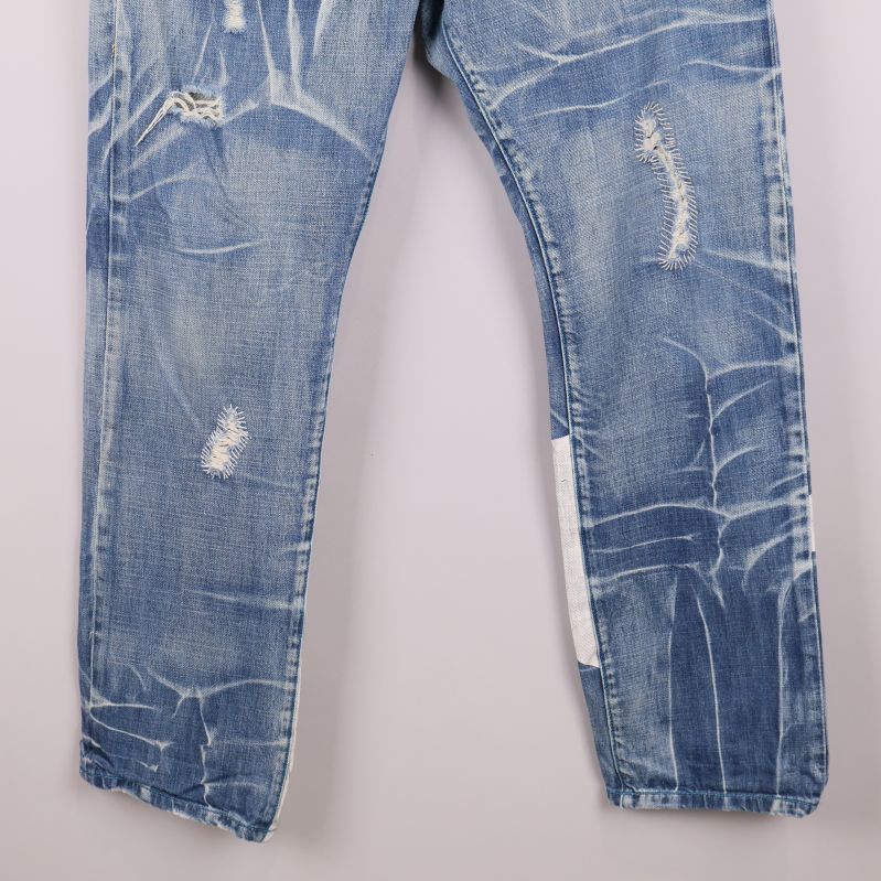 Närbild på jeansbenens nedre del med synliga slitningar