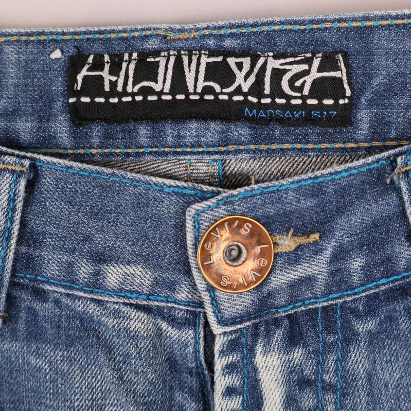 Närbild på midjans etikett och knapp på jeansen