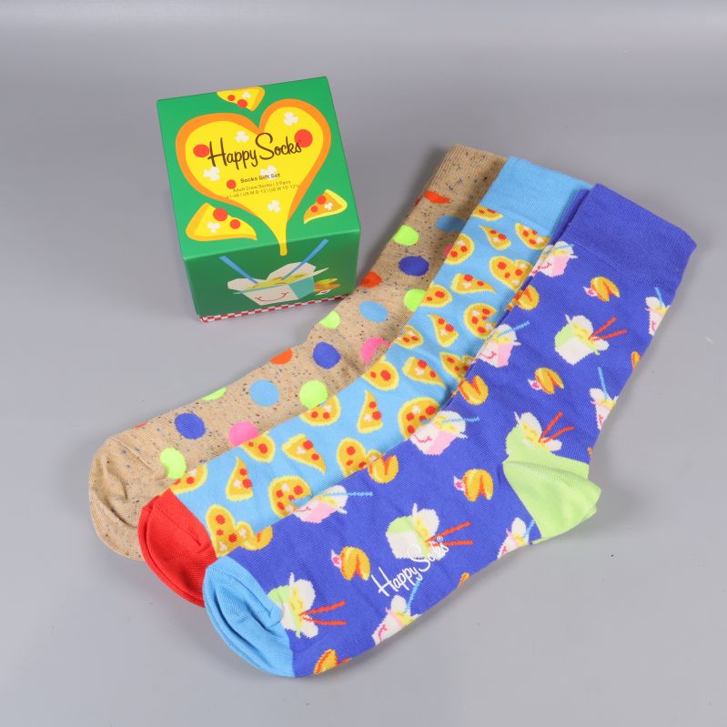 Tre par färgglada strumpor med olika matmönster bredvid grön kartong