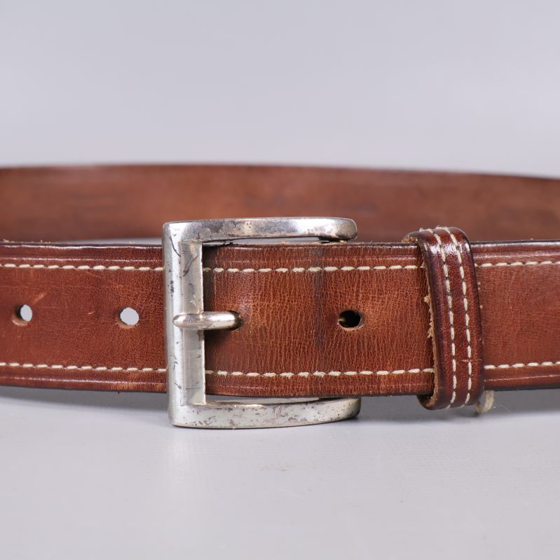 Närbild på spänne och hål på brunt läderbälte