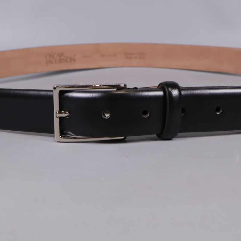 Närbild på spänne och hål av svart skärp i läder