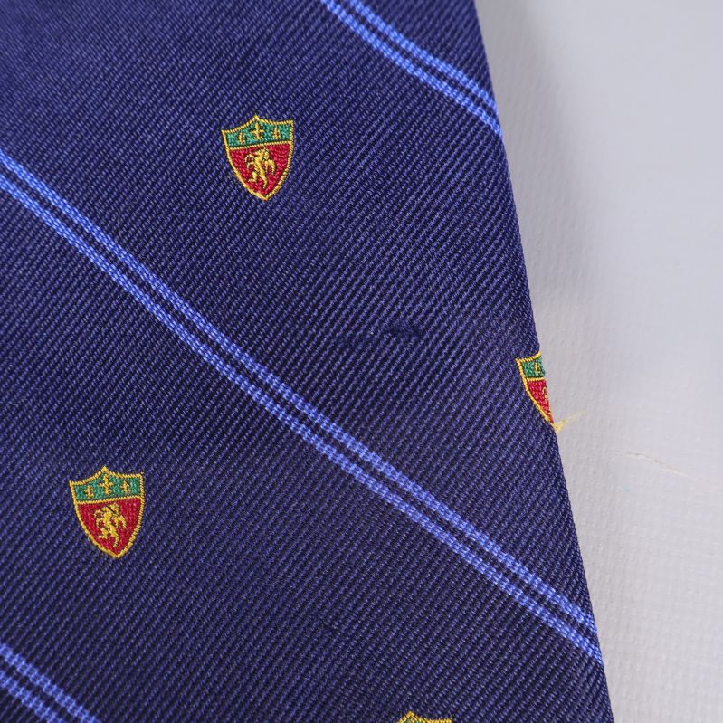 Närbild på tygmönster och emblem på slips