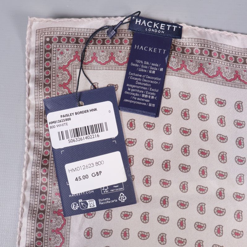 Två etiketter från Hackett London bredvid tygkanter och paisleymönster