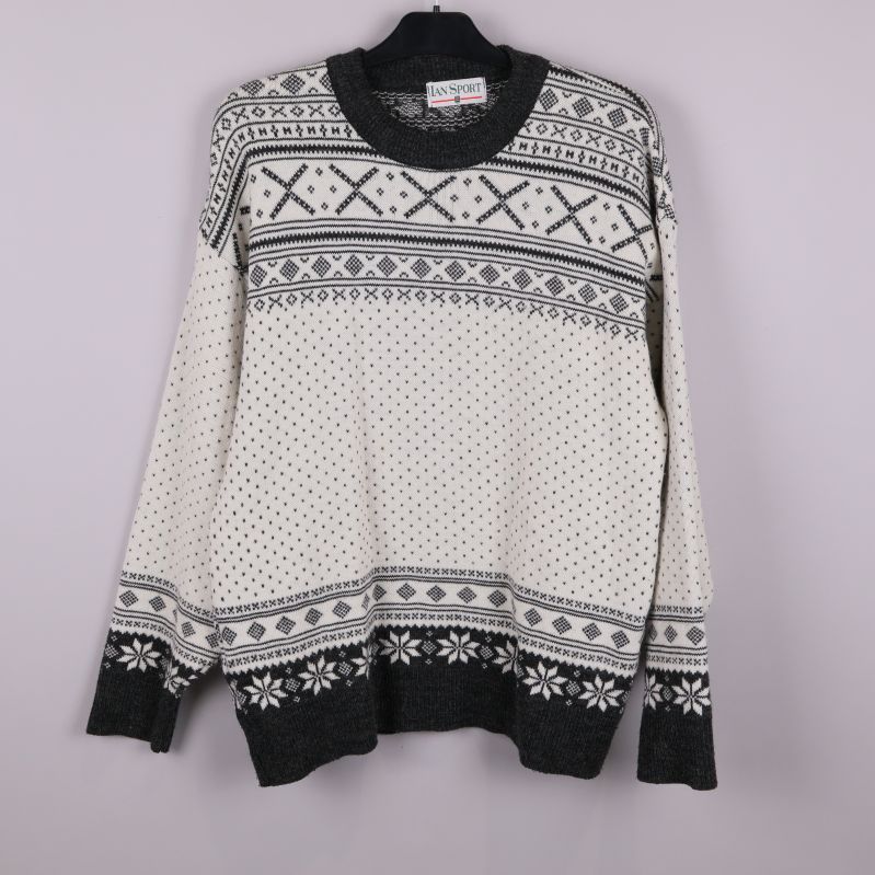 Stickad tröja upphängd framifrån med svartvitt grafiskt mönster