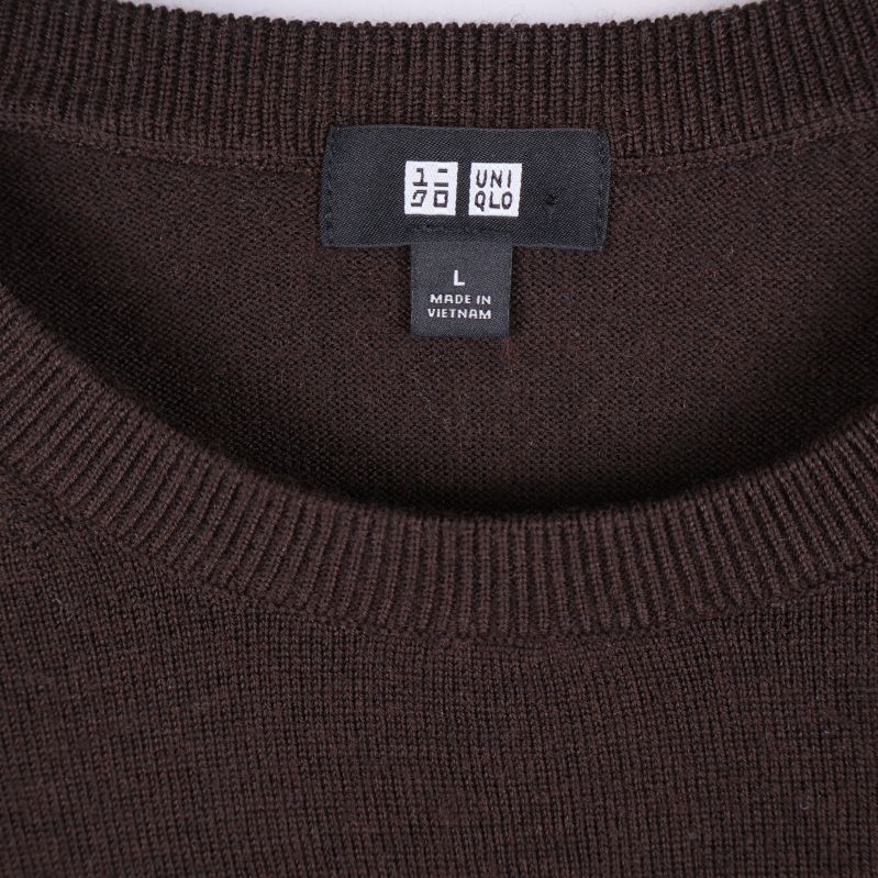 Närbild på Uniqlo-logo och halsringning på brun tröja