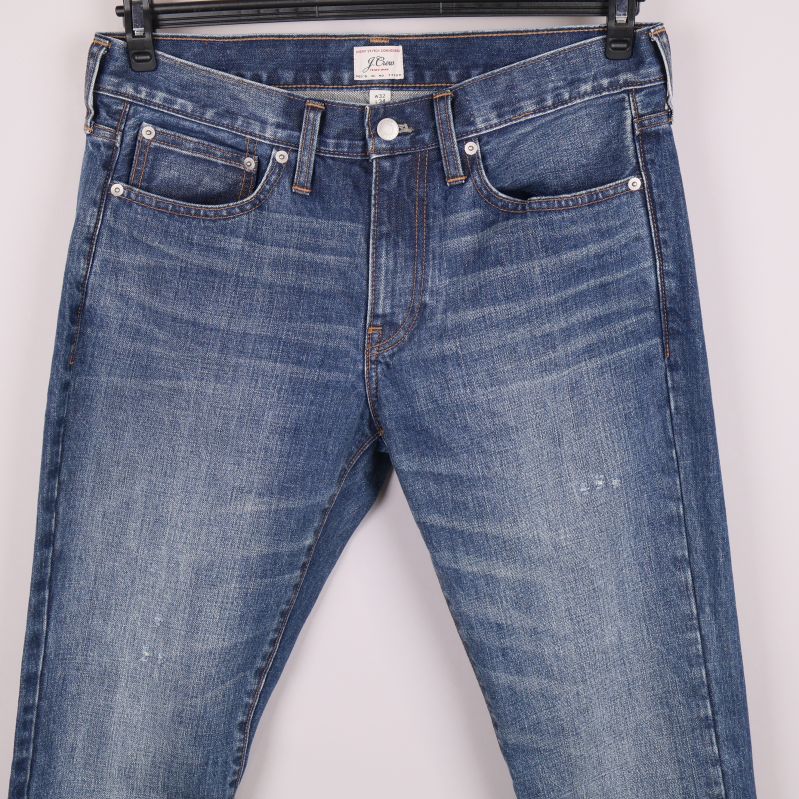Närbild på framsida av blå jeans med subtila slitningar
