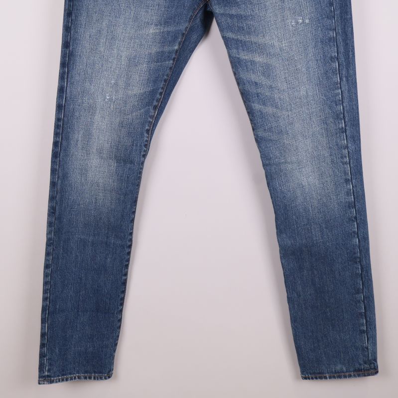 Ben på blå jeans med markerad tvätt och slitning