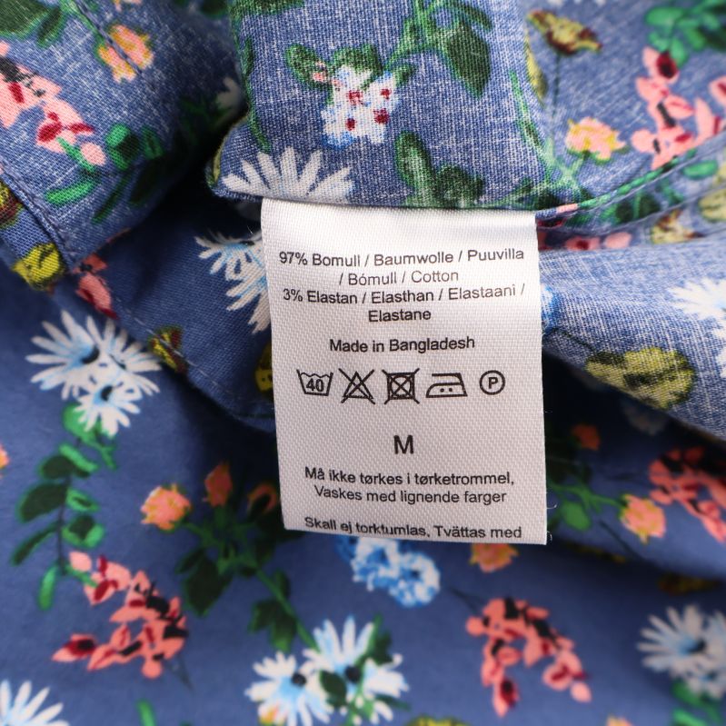 Tvättrådsetikett med materialinfo i blommig skjorta