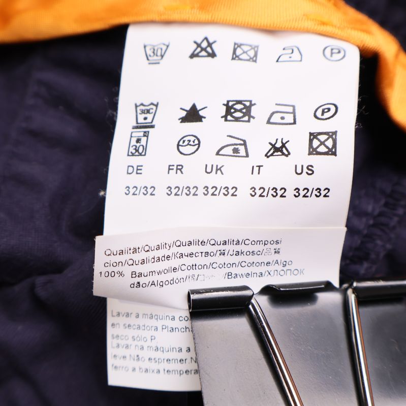 Tvättetikett som visar material och storlek 32/32 i bomull