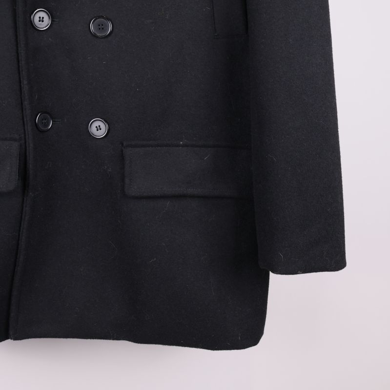 Närbild på knapp och ficka på svart kappa