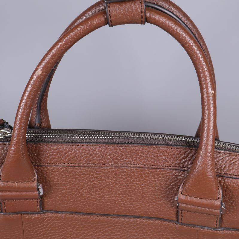 Närbild på handtag och blixtlås i brunt skinn