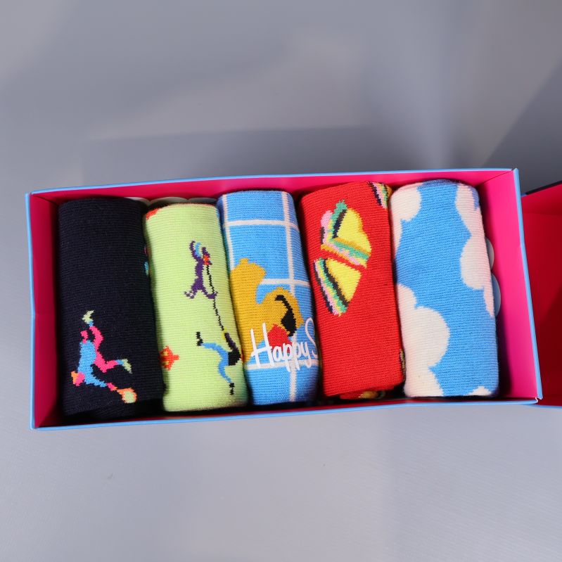 Fem hoprullade strumpor i olika färger och motiv i ask