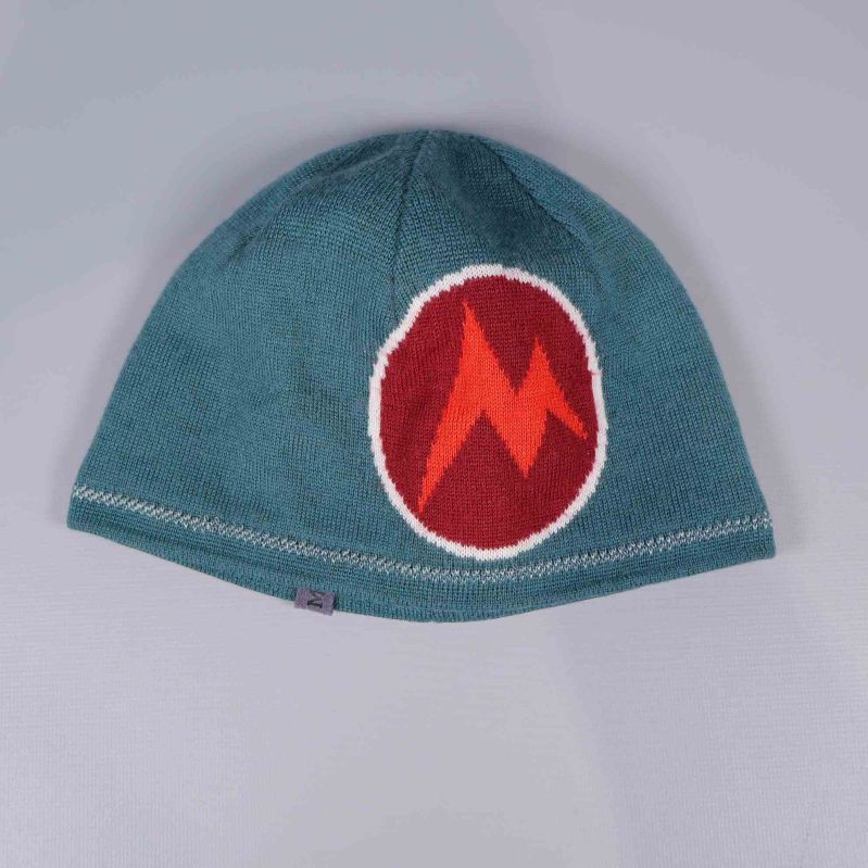 Hel mössa i grönblått med stort rött zigzagmärke framtill