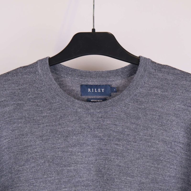 Närbild på halsringning av grå stickad tröja