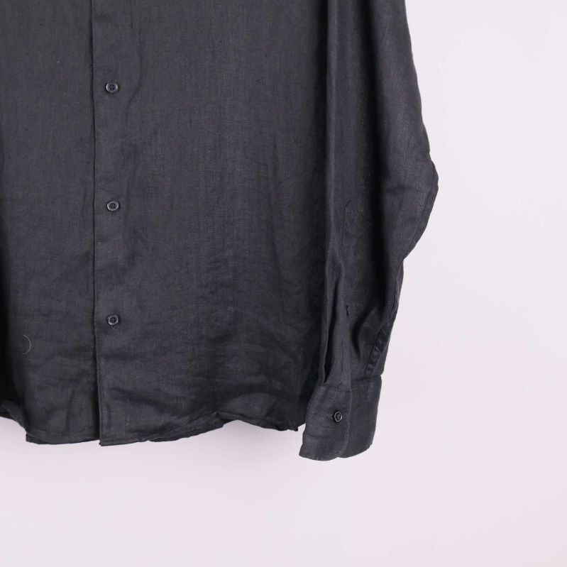 Nederkant av svart skjorta med knappslå och manschett