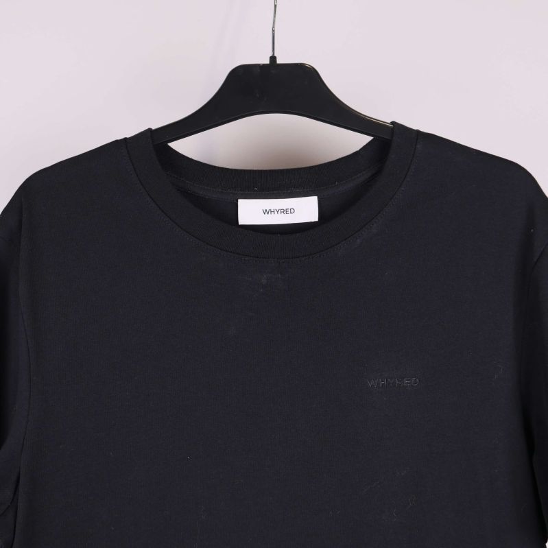 Närbild upptill på svart t-shirt med diskret ton-i-ton logga