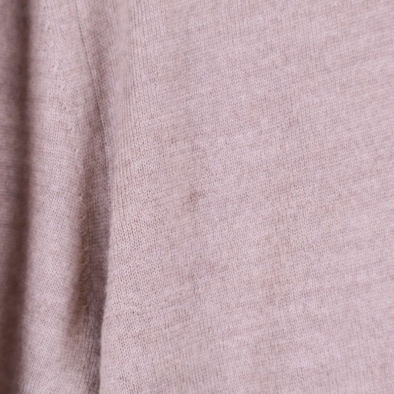 Närbild på materialets struktur på den beige ulltröjan