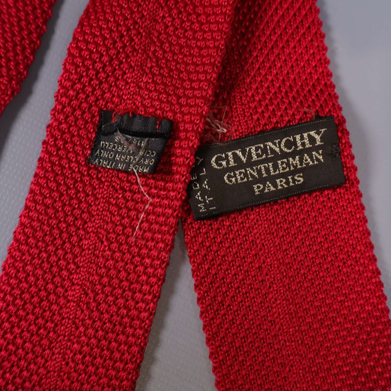 Närbild av Givenchy etikett och tillverkningslapp på röd slips