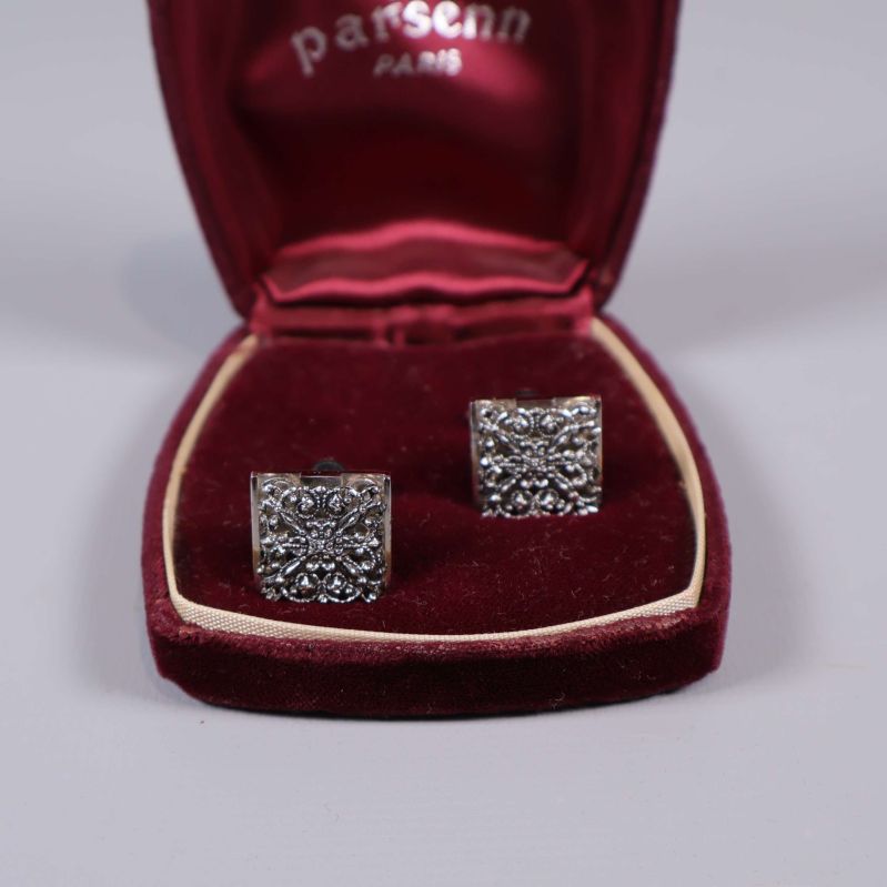 Närbild på två silverfärgade manchettknappar