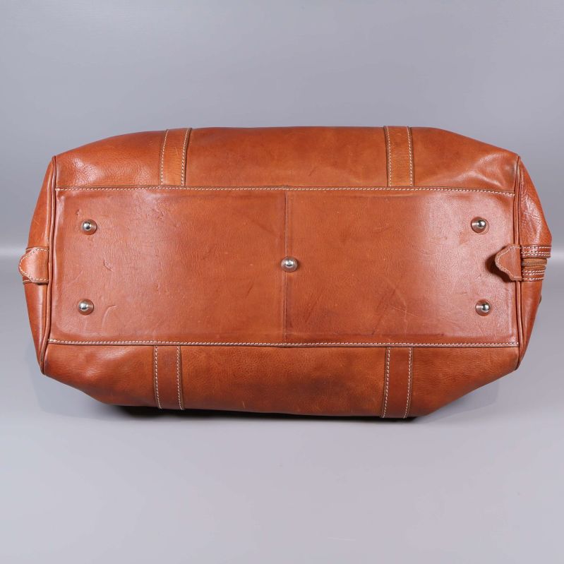 Väskans botten i cognacsfärgat läder med metallfötter