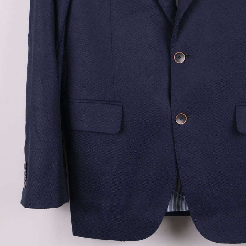 Närbild på kavajens nedre framdel med fickor och knäppning