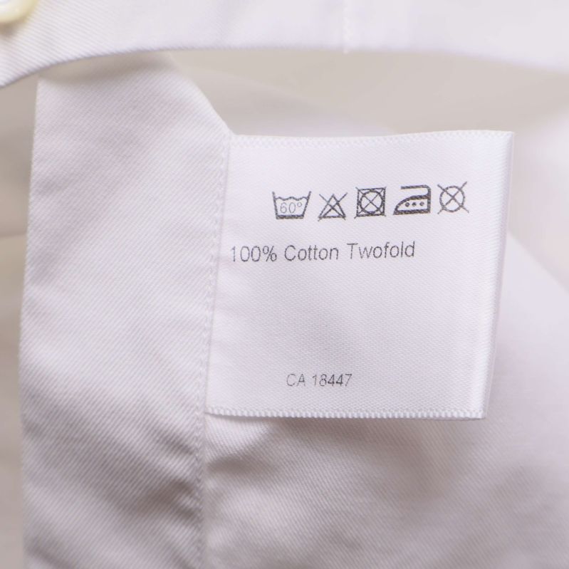 Tvättlapp med materialinformation och tvättråd i vit skjorta