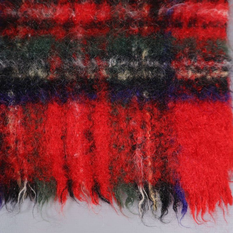 Närbild på rutigt garn och fransar i halsduk