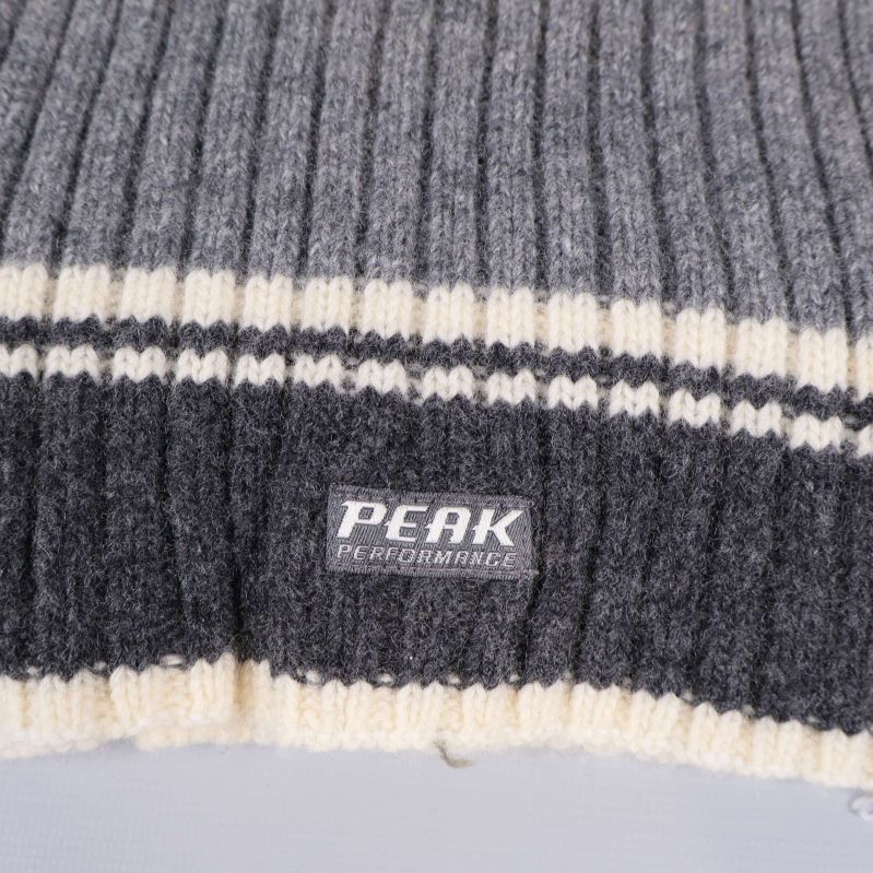 Närbild på Peak Performance logotyp och randdetalj på halsduk