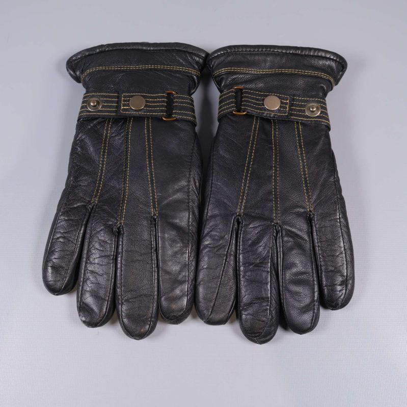 Handskar liggande med knappar och synliga guldsömmar ovanifrån