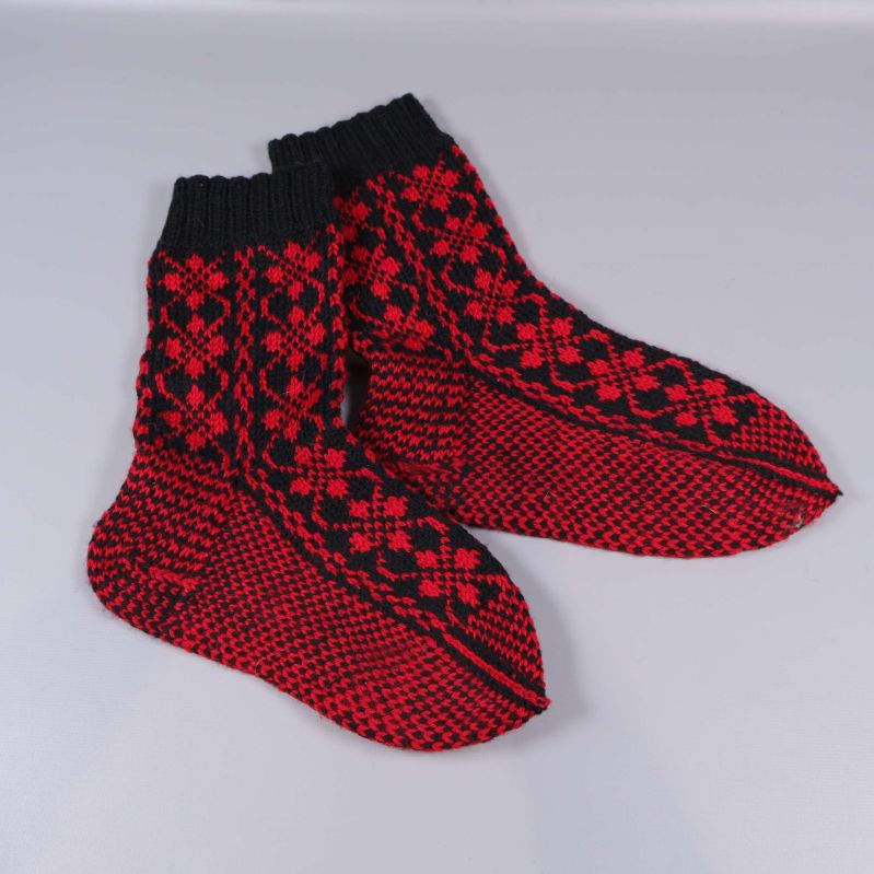 Stickade strumpor med svart kant och röd botten, liggande platt