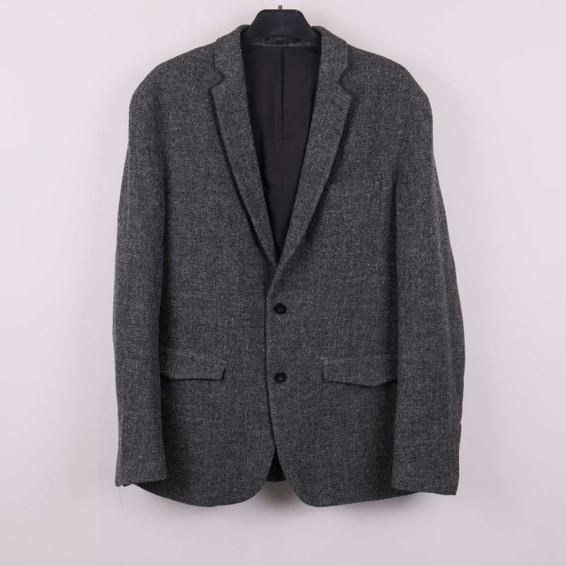 Mörkgrå kavaj upphängd på galge sedd framifrån