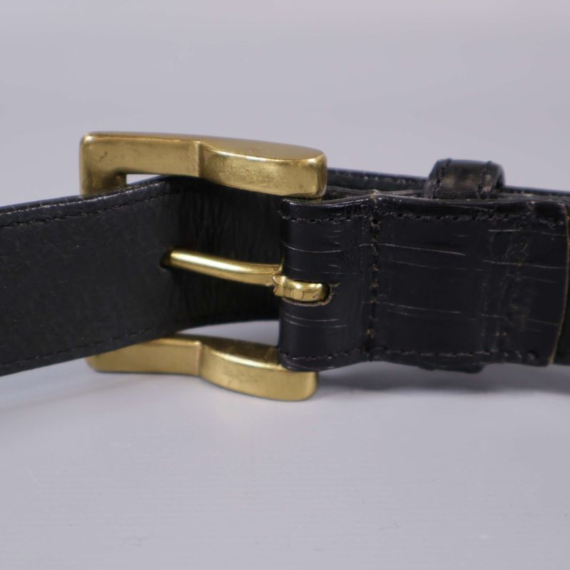 Närbild baksidan av bältet med spännet i guldfärg