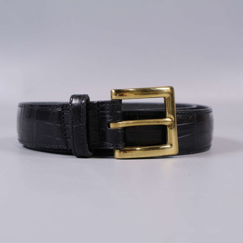 Upprullat svart bälte med gyllene spänne framifrån