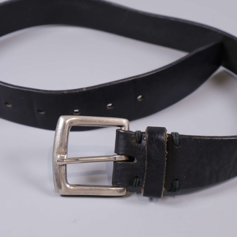 Svart bälte liggande med synligt spänne och flertalet hål