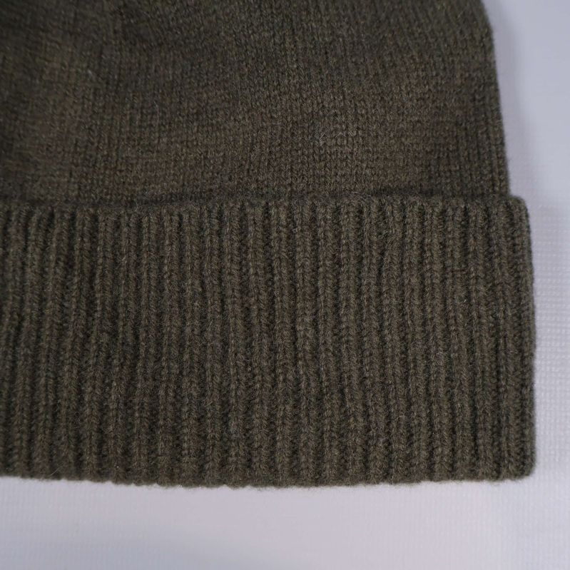 Närbild på ribbad kant av olivgrön mössa