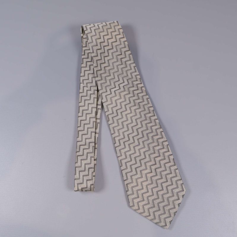 Slips i beige nyans liggande på grå bakgrund