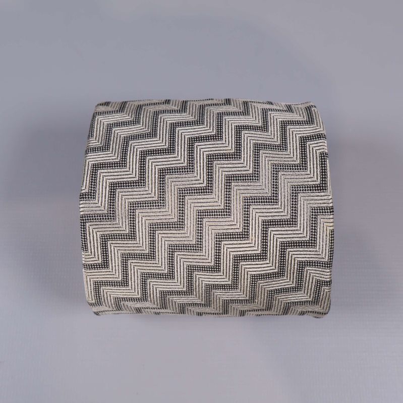 Rullad slips med fiskbensmönster liggande på grå yta