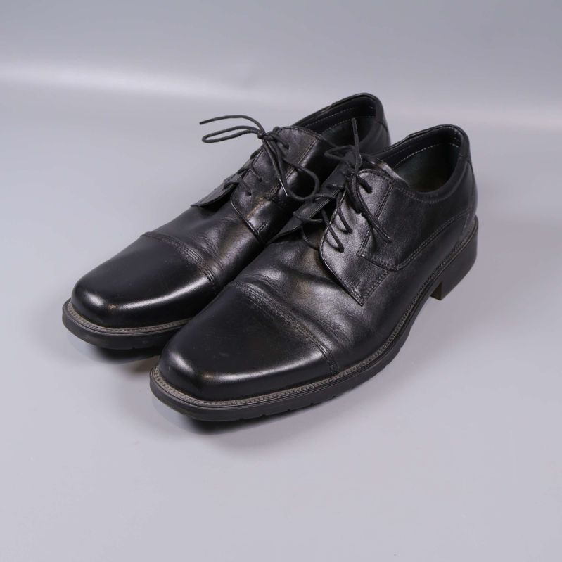 Klassiska svarta finskor i sned vinkel på grå bakgrund