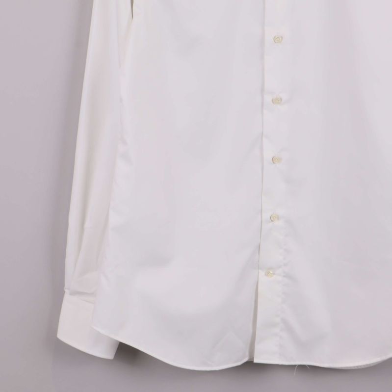 Närbild på nederkant och ärmslut av vit skjorta