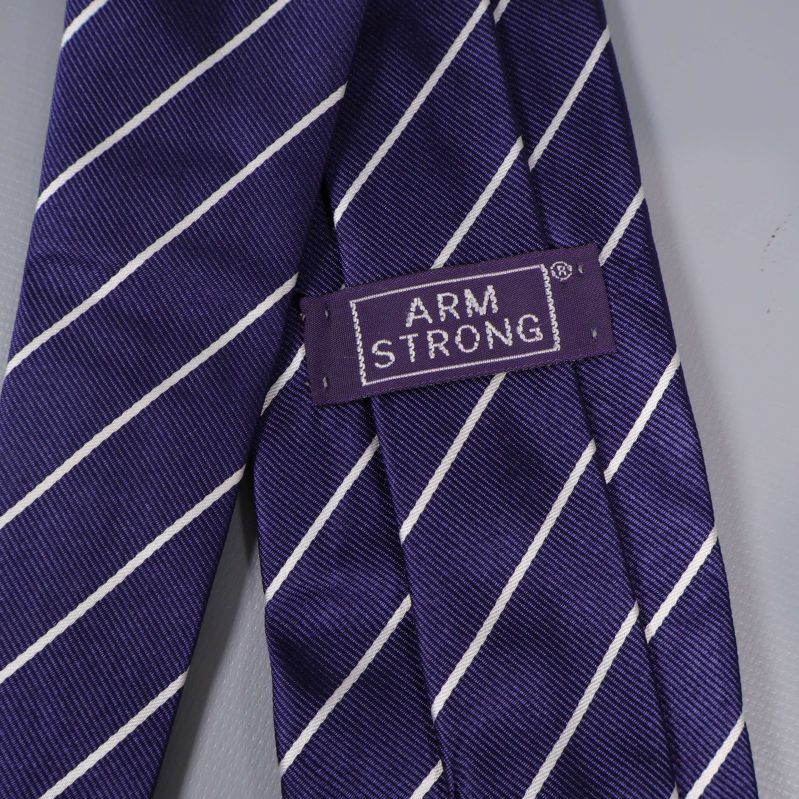Närbild på Armstrong-märke på blå slips