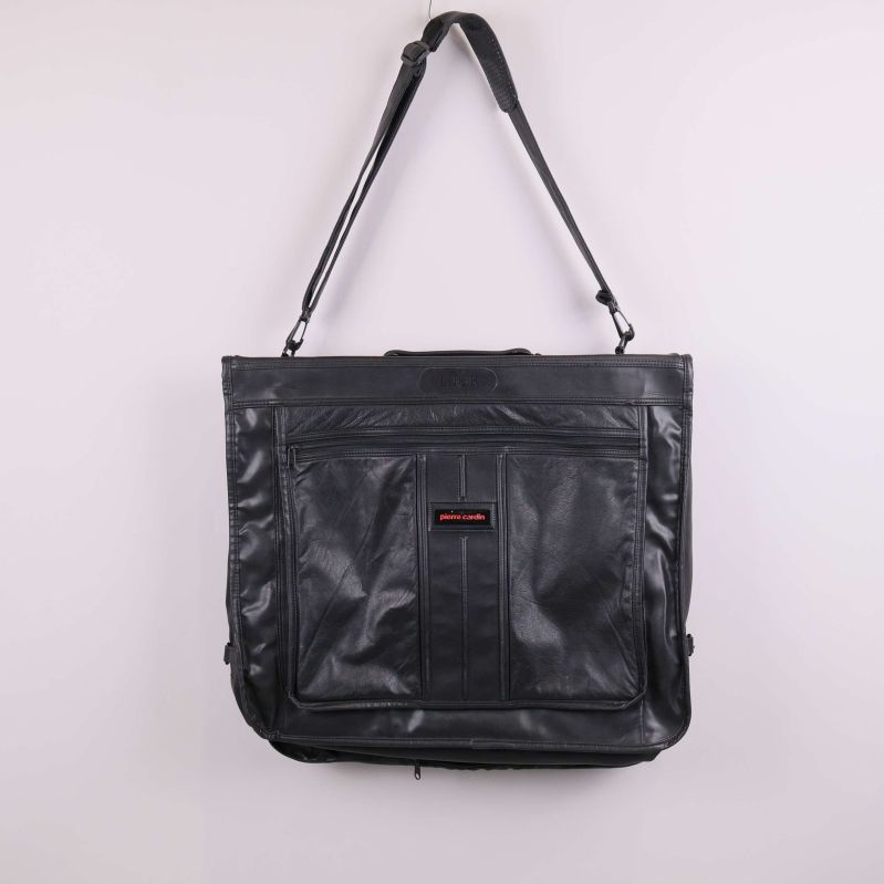 Stor svart portfölj med justerbar axelrem hänger mot ljus bakgrund