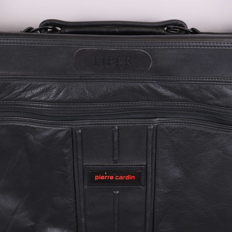 Närbild på pierre cardin-logotyp och detaljer på svart portfölj