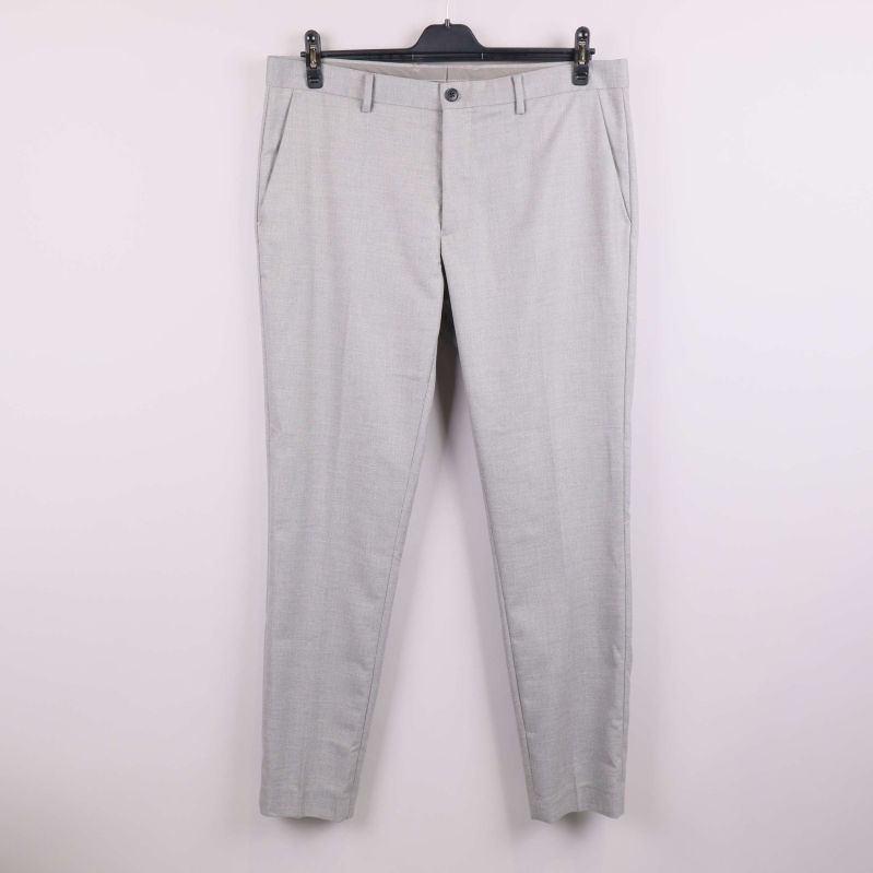 Slim fit ljusgrå kostymbyxa hänger mot vit vägg