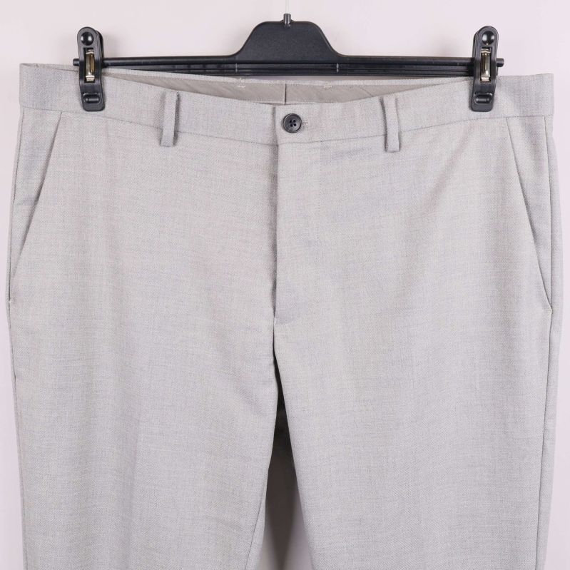 Närbild av framfickor och midjeknapp på ljusgrå byxa