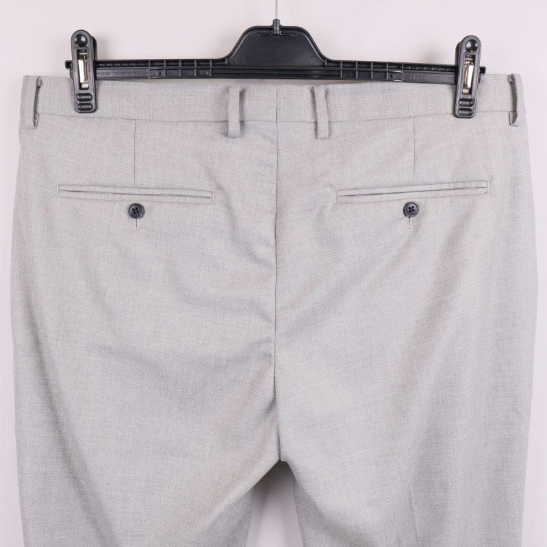 Närbild av dubbla bakfickor på ljusgrå kostymbyxa