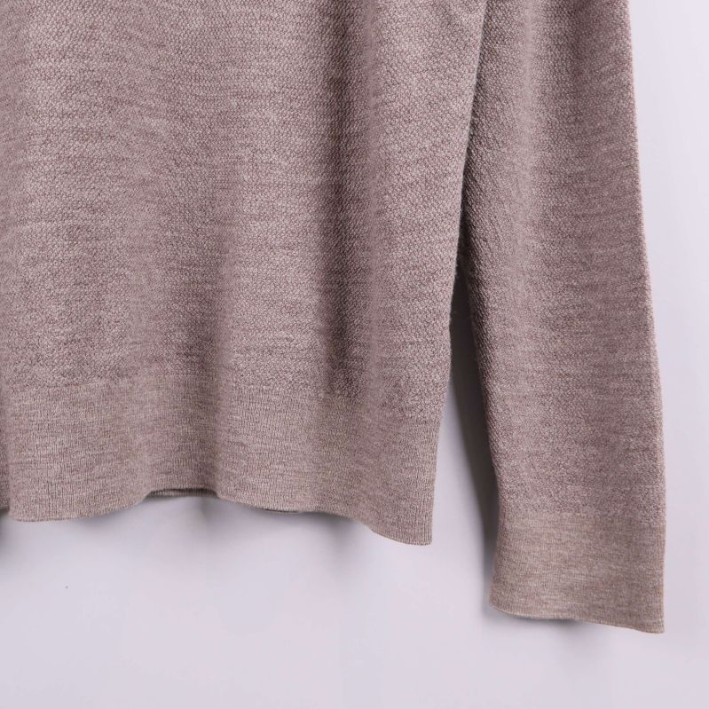 Detalj av nederkant på stickad tröja och avslut på vänster ärm